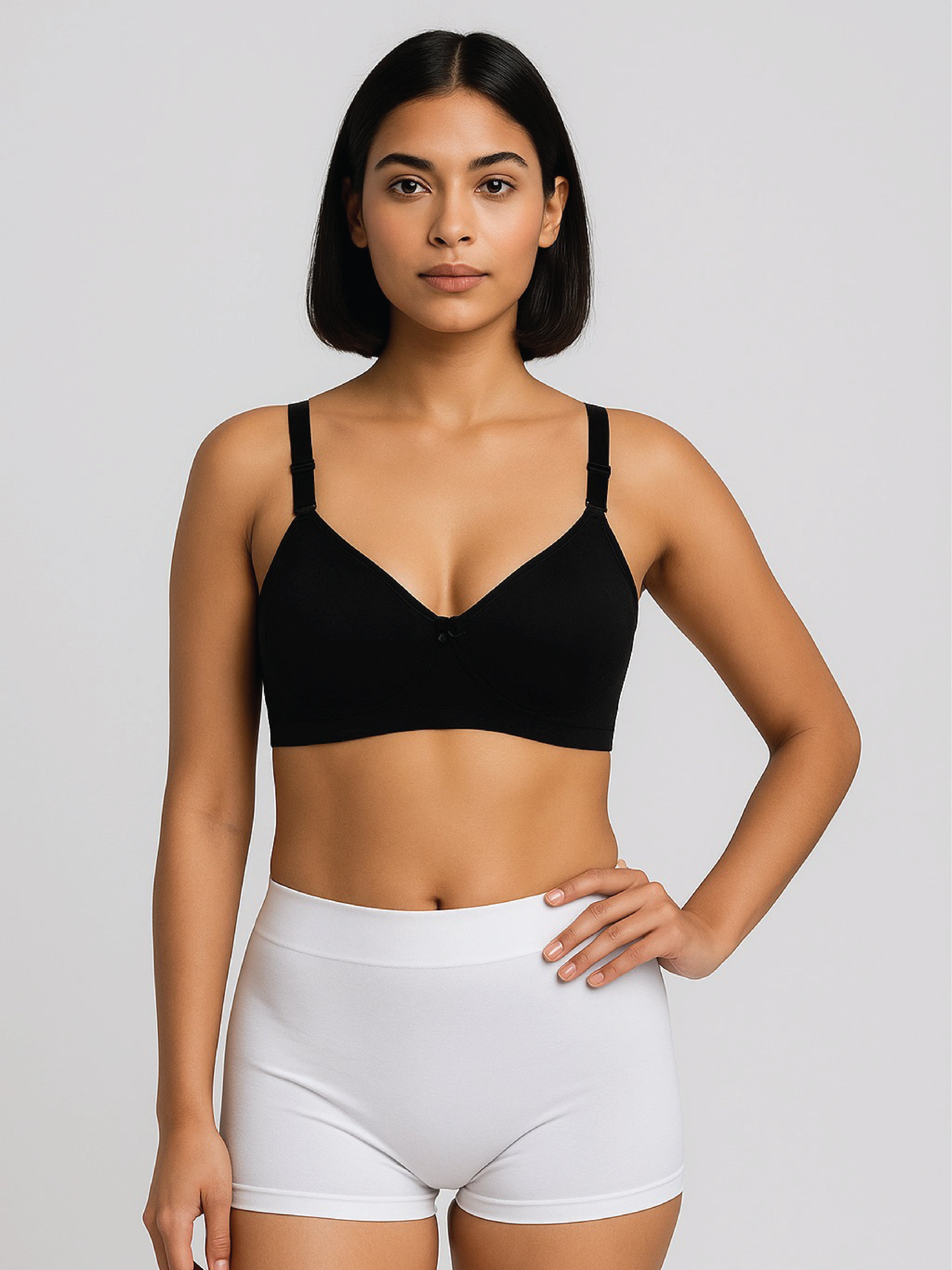 Woman wearing a black sports bra and white shorts on a plain background